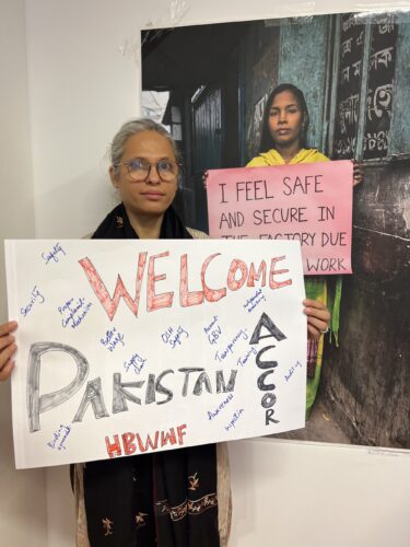 ZehraKahn of the Home-Based Women Workers Association holds a sign reading "Welcome Pakistan Accord"